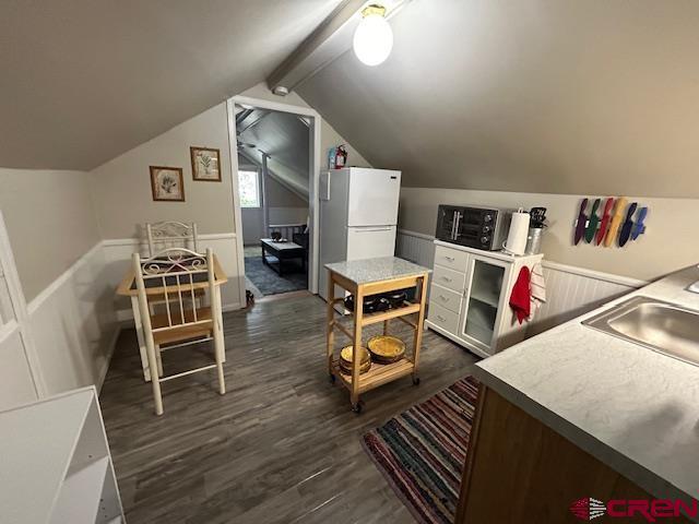 interior space with sink, dark wood-type flooring, and vaulted ceiling