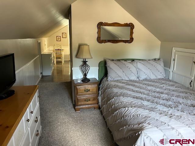 bedroom with vaulted ceiling and dark carpet