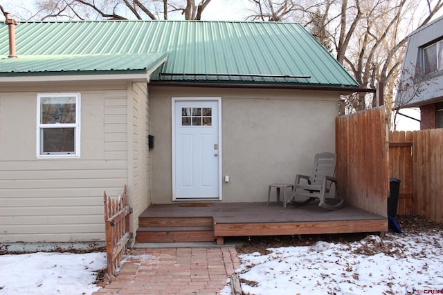 snow covered property entrance featuring a deck