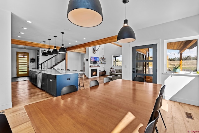 dining room featuring beam ceiling and light hardwood / wood-style floors