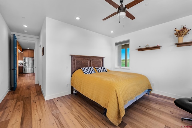 bedroom featuring ceiling fan, light hardwood / wood-style floors, and stainless steel fridge with ice dispenser