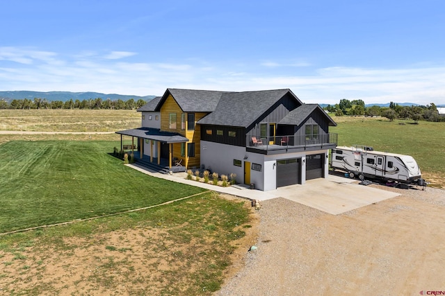 view of front of home with a mountain view, a garage, a front yard, a balcony, and a rural view