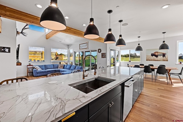 kitchen featuring light stone counters, stainless steel dishwasher, sink, vaulted ceiling with beams, and hanging light fixtures