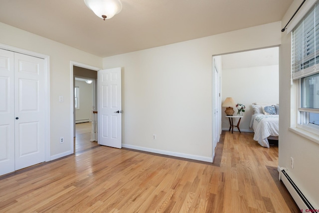 bedroom with light hardwood / wood-style flooring, a closet, and a baseboard heating unit