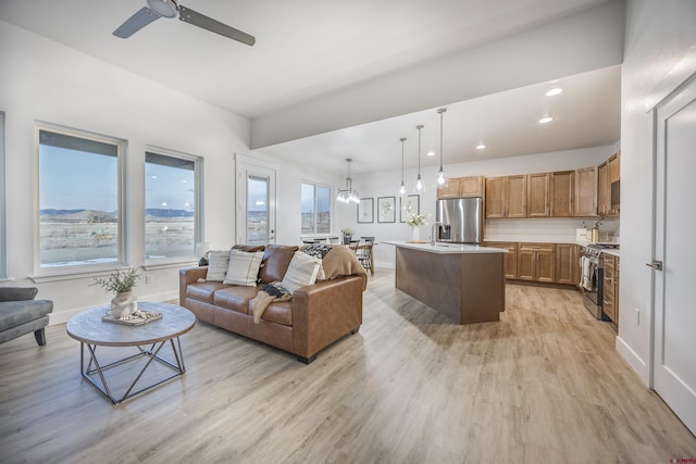 living room with ceiling fan with notable chandelier and light wood-type flooring