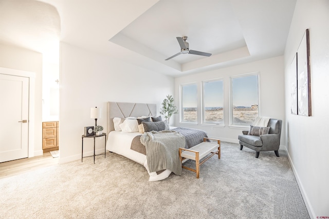 carpeted bedroom featuring ceiling fan and a tray ceiling