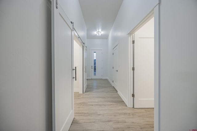 hallway featuring a barn door and light hardwood / wood-style floors