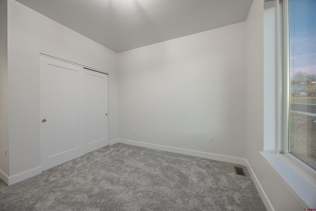 unfurnished bedroom featuring light carpet and a closet