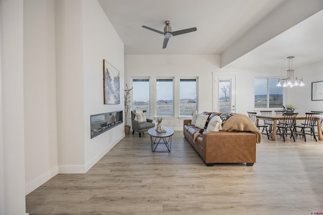 living room featuring ceiling fan with notable chandelier, light hardwood / wood-style floors, and a healthy amount of sunlight