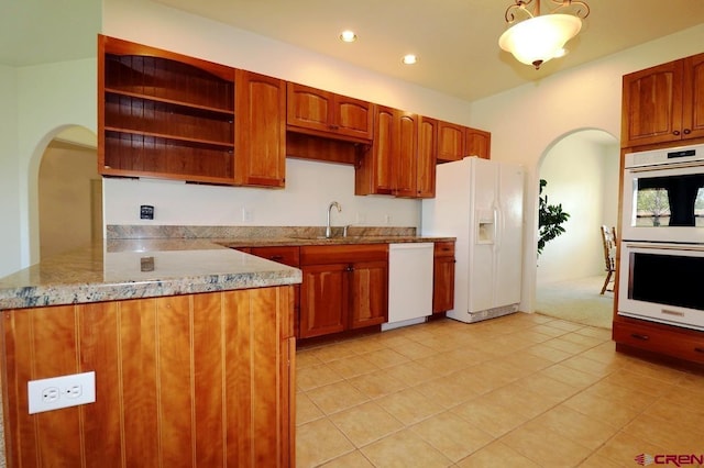 kitchen with kitchen peninsula, white appliances, decorative light fixtures, and light tile patterned flooring