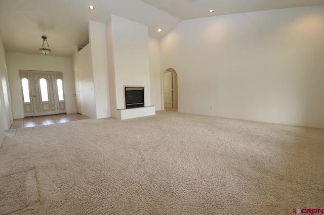 unfurnished living room with light carpet and high vaulted ceiling