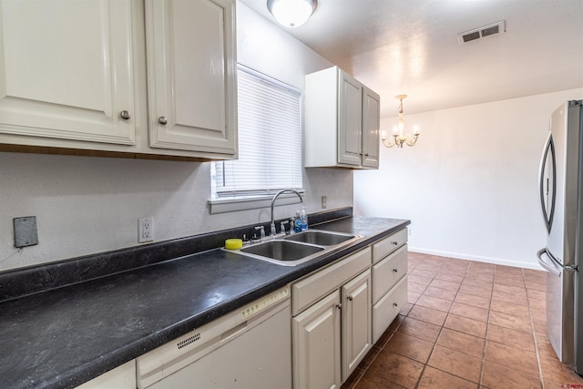 kitchen with an inviting chandelier, white dishwasher, sink, light tile patterned floors, and stainless steel refrigerator