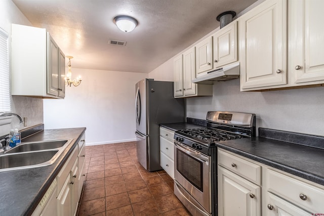 kitchen with dark tile patterned flooring, sink, appliances with stainless steel finishes, white cabinetry, and a chandelier