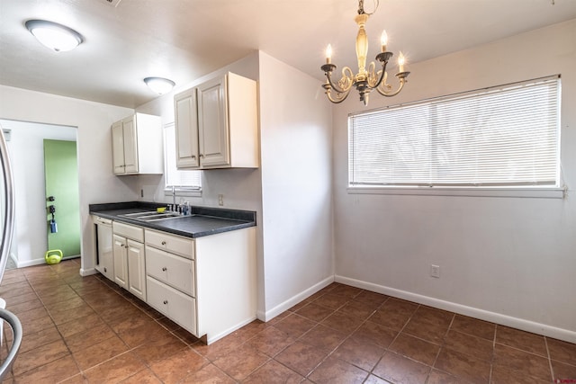 kitchen with a wealth of natural light, sink, an inviting chandelier, pendant lighting, and white cabinets