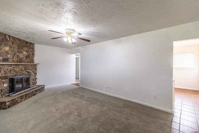 unfurnished living room featuring ceiling fan, a stone fireplace, carpet floors, and a textured ceiling