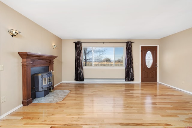 foyer entrance with light hardwood / wood-style flooring, a wood stove, and a baseboard radiator