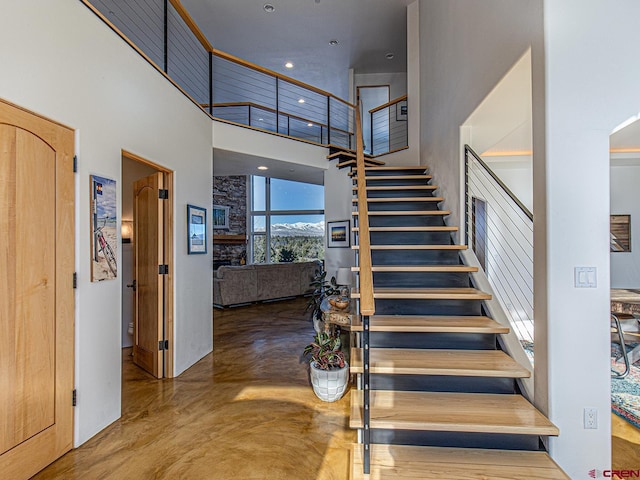 stairs featuring a towering ceiling and a fireplace