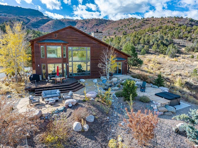 rear view of house featuring a deck with mountain view, a patio area, and an outdoor living space