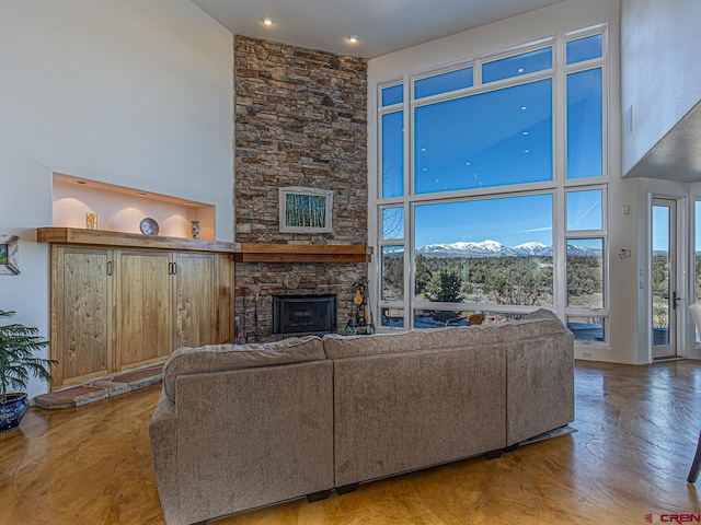 living room with a high ceiling, a mountain view, and a stone fireplace