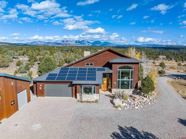 view of front of house with solar panels, a garage, and a mountain view