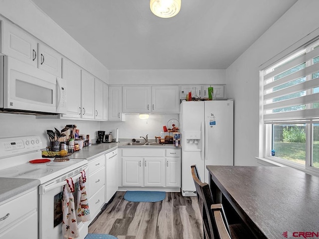 kitchen with white cabinets, light wood-type flooring, white appliances, and sink