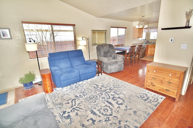 living room with sink, an inviting chandelier, vaulted ceiling, and light wood-type flooring