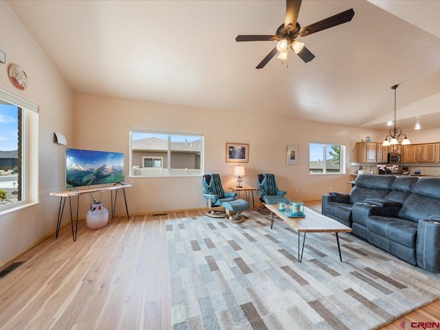 living room featuring ceiling fan with notable chandelier, light hardwood / wood-style flooring, and vaulted ceiling