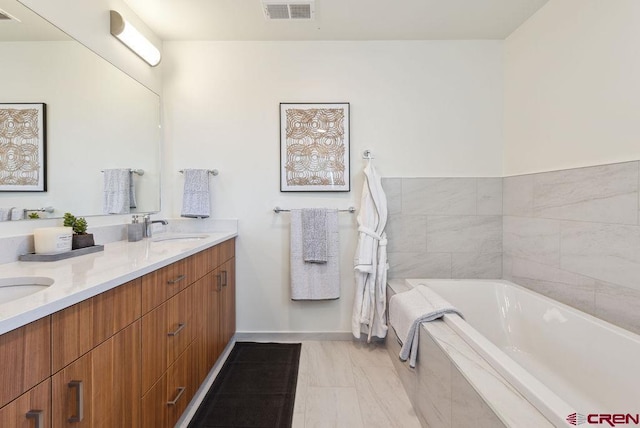 bathroom with visible vents, a sink, a bath, and double vanity