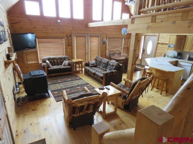 living room with a towering ceiling, light hardwood / wood-style floors, and wood walls