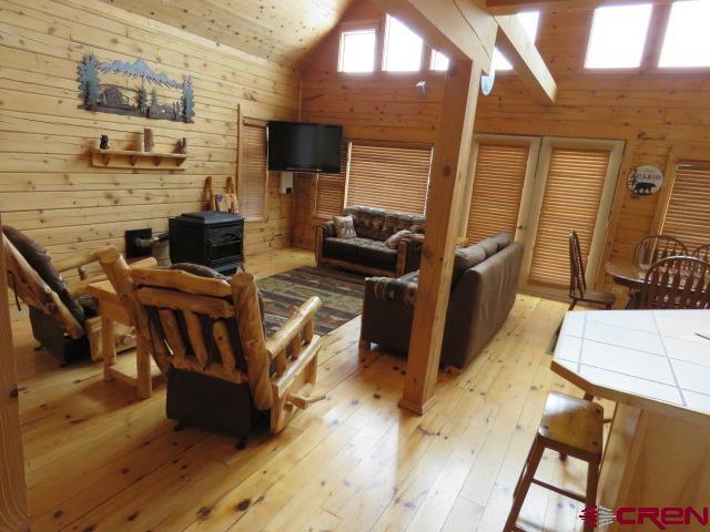 living room featuring wood walls, light hardwood / wood-style floors, and high vaulted ceiling