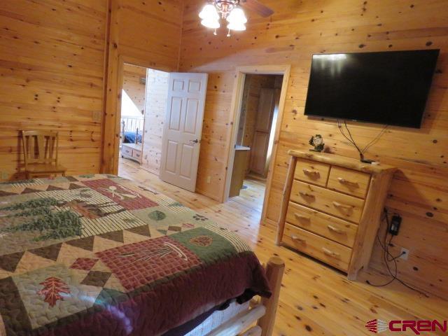 bedroom with light hardwood / wood-style flooring and wood walls