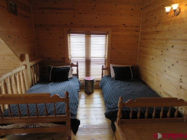 bedroom featuring wooden walls and hardwood / wood-style flooring