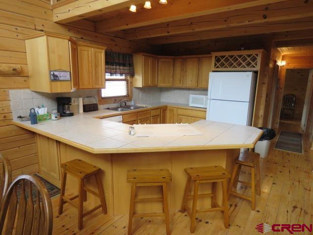 kitchen featuring sink, tasteful backsplash, tile countertops, kitchen peninsula, and white appliances