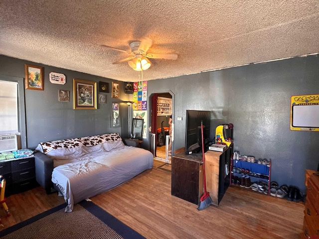 bedroom with a textured ceiling, hardwood / wood-style flooring, and ceiling fan