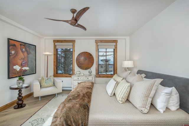 bedroom featuring hardwood / wood-style flooring, a baseboard radiator, and ceiling fan