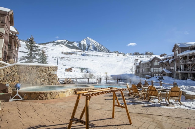 snow covered patio with a mountain view and a community hot tub