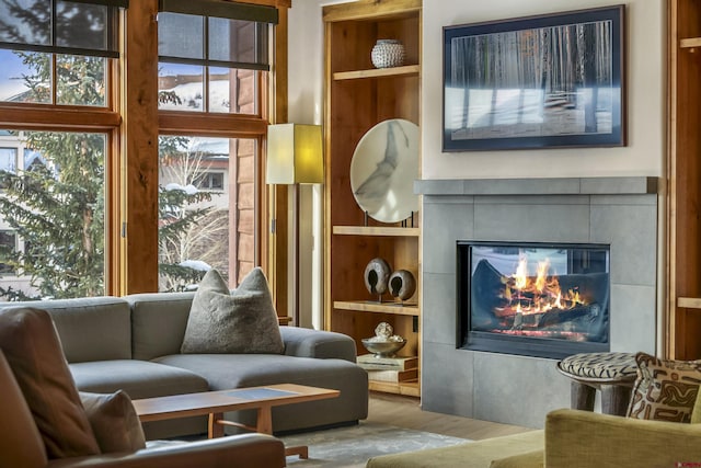 sitting room with a healthy amount of sunlight, wood-type flooring, and a tile fireplace