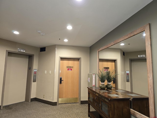 hallway featuring light colored carpet and elevator