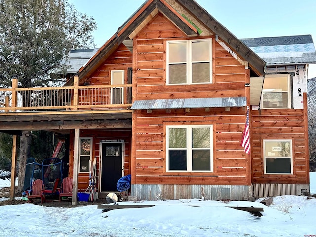 snow covered rear of property with a wooden deck