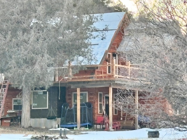 snow covered back of property with a balcony