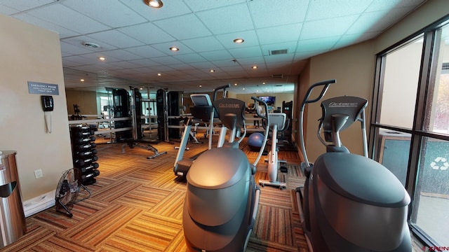 workout area featuring a paneled ceiling and light colored carpet