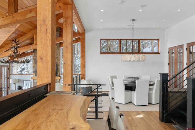 dining space with wood ceiling, beamed ceiling, a chandelier, and light hardwood / wood-style floors