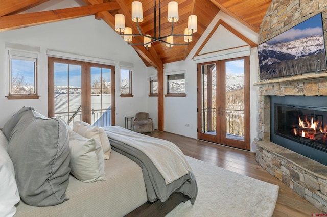 bedroom featuring french doors, vaulted ceiling with beams, access to outside, and a stone fireplace