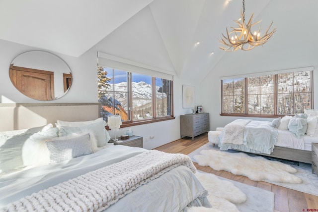 bedroom with hardwood / wood-style flooring, lofted ceiling, and an inviting chandelier