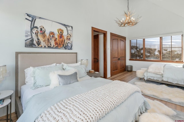 bedroom featuring a chandelier, light wood-type flooring, and vaulted ceiling