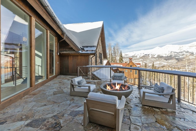 snow covered back of property with a mountain view and a fire pit