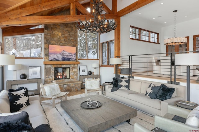 living room with wood-type flooring, high vaulted ceiling, an inviting chandelier, beamed ceiling, and a stone fireplace