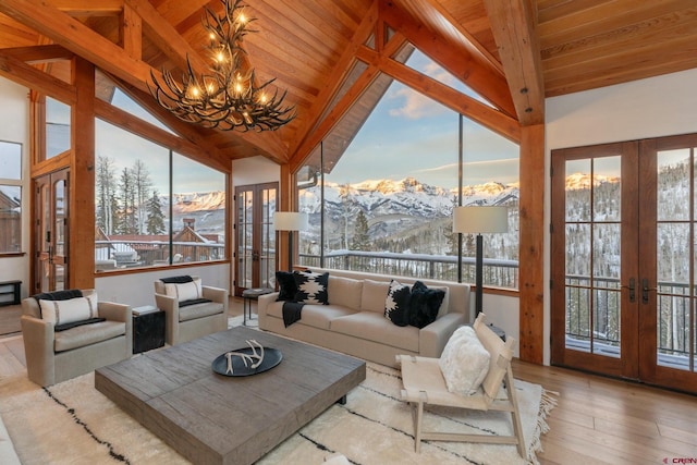 sunroom / solarium with a mountain view, french doors, lofted ceiling with beams, and a notable chandelier