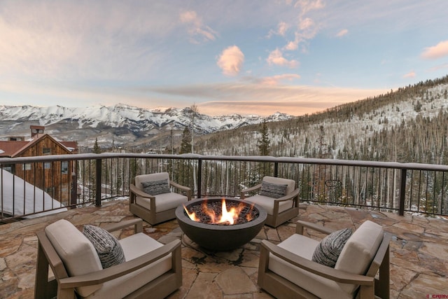 snow covered patio featuring a mountain view and a fire pit