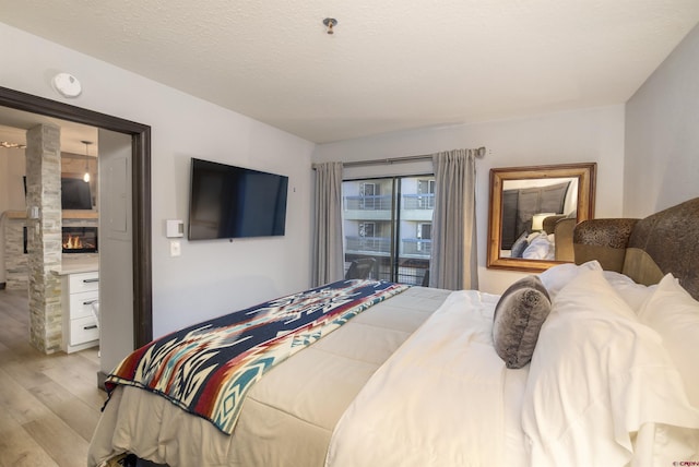 bedroom featuring a fireplace, a textured ceiling, and light wood-type flooring